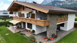 a woman standing in front of a house with a balcony at Appartement Fischer in Sankt Johann in Tirol