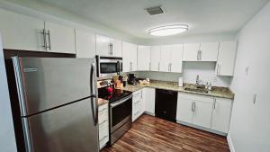 a kitchen with white cabinets and a stainless steel refrigerator at The Lofts on Clematis 405 Downtown West Palm Beach in West Palm Beach
