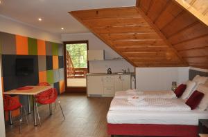 a bedroom with a bed and a table and a kitchen at Apartamenty Lawenda in Rabka