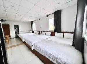 uma fila de camas num quarto com paredes brancas em Hoài Thu Hotel Vũng Tàu em Vung Tau