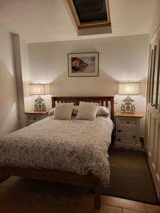 a bedroom with a bed with two night stands and two lamps at Barn Owl in Happisburgh