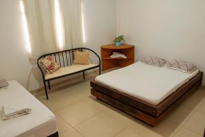 een kamer met 2 bedden en een stoel. bij Quartos no centro de Três Marias in Três Marias