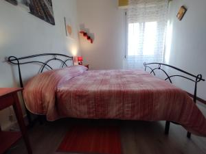 1 dormitorio con 1 cama con edredón rojo y ventana en Damarilù, en Alghero