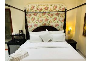 ein Schlafzimmer mit einem großen weißen Bett mit einem floralen Kopfteil in der Unterkunft Hotel Jaipur Dreams in Jaipur