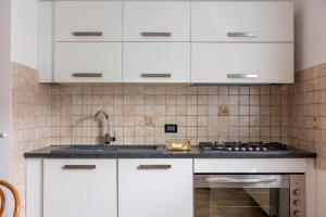 a kitchen with white cabinets and a stove at Mara House, Fino del Monte Ospitar in Fino del Monte