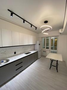a large kitchen with white cabinets and a table at K7 Family in Atyraū