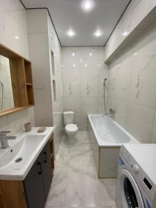 a bathroom with a toilet sink and a washing machine at K7 Family in Atyraū