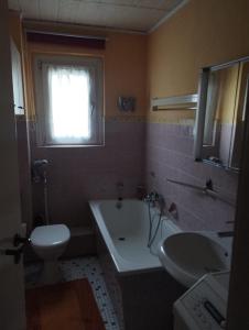 a bathroom with a tub and a toilet and a sink at Red Dot Apartments in Kamen