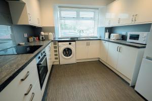 a kitchen with white cabinets and a washer and dryer at Modern 3 Bedroom home. A perfect base for Golfers in Ladybank