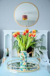 un vase de fleurs sur une table en verre avec un miroir dans l'établissement Modern 3 Bedroom home. A perfect base for Golfers, à Ladybank
