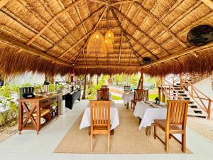 um restaurante com mesas e cadeiras debaixo de um guarda-sol de palha em Hotel Azulea Bacalar - Lagoon Front em Bacalar