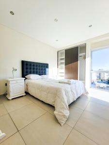 a white bedroom with a large bed and a window at Espacio Chacabuco in Comodoro Rivadavia