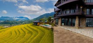 a house on a hill next to a field of grass at Black Ship Sapa in Sapa