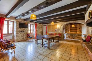 Habitación grande con mesa, sillas y chimenea. en Maison de l Albine, gite de groupe, en Peyrusse-le-Roc