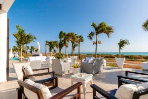 patio z krzesłami i stołami oraz plaża w obiekcie Hotel LIVVO Budha Beach w mieście Santa Maria