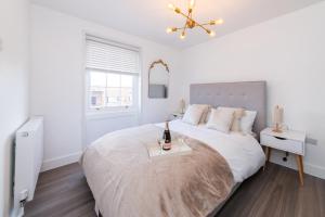 Dormitorio blanco con cama y bandeja con una botella de vino en 3 Bed Exceptional Stay, en Reading