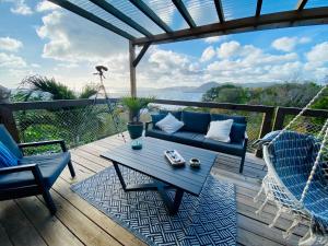 eine Terrasse mit einem blauen Sofa und Stühlen auf einer Terrasse in der Unterkunft Anoli Lodges in Sainte-Anne