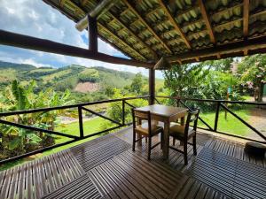 a table and two chairs on a deck with a view at Pousada A Mata que Canta in Socorro
