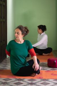 Duas mulheres sentadas no chão numa pose de ioga. em Casa Rural Los Sentidos Jimena em Jimena de la Frontera