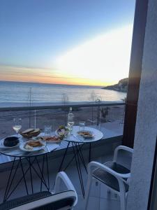 a table with plates of food on a balcony with the beach at Anxhelos Hotel in Himare