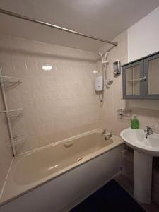 a bathroom with a bath tub and a sink at Spacious one bed flat in eastlondon with parking and free wifi in Goodmayes