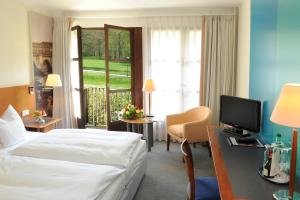 
a room with a bed, a desk, and a television at Hotel Schloss Eckberg in Dresden
