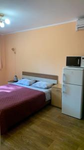 1 dormitorio con 1 cama y nevera. en База відпочинку «Павлоградець», en Orlovshchina