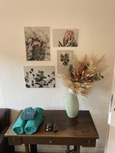 einen Tisch mit einer Vase und Bildern an der Wand in der Unterkunft 3-Zimmer-Wohnung / 10min vom ICE in Siegburg