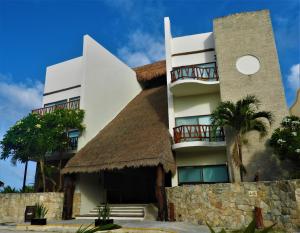 a large white building with a thatch roof at Quinto Sole by GuruHotel in Mahahual