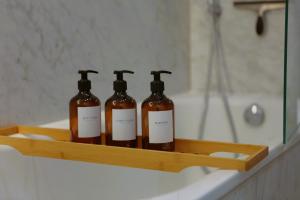 three bottles of soap sitting on a shelf next to a bath tub at Cosy Stay Soho London in London
