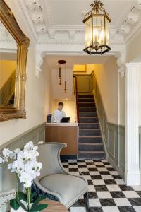a man standing at a counter in a lobby with a staircase at Stone Villa Chester in Chester