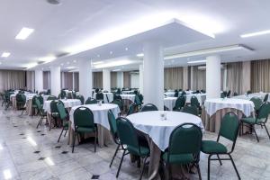 un salón de banquetes con mesas blancas y sillas verdes en Umuarama Plaza Hotel by Castelo Itaipava, en Goiânia