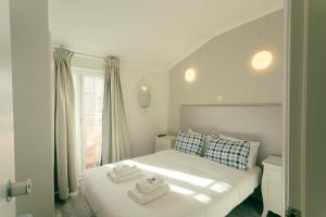 Un dormitorio con una cama blanca con toallas. en Best Houses Portugal Residence, en Peniche