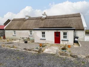a white house with a red door and a picnic table at Freemans Cottage in Enniscrone