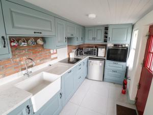 a kitchen with blue cabinets and a brick wall at Freemans Cottage in Enniscrone