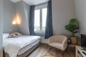 a bedroom with a bed and a chair and a window at Homey Studios - City Centre in The Hague