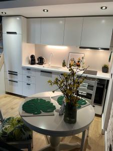 a kitchen with a table with a vase of flowers on it at Piotrkowska 37 - Green Leaf in Łódź +16 photos