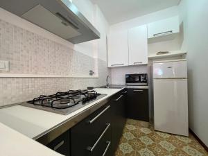 a kitchen with a stove and a white refrigerator at Appartamento Fiore in Follonica