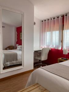 1 dormitorio con espejo, cama y escritorio en Posada Las Torres, en Yuso
