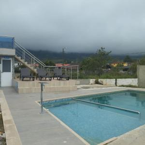 a swimming pool with two benches next to a building at HOTEL DE LOS COLORES in Papagalleros