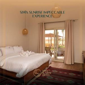 Siwa Sunrise Hotel في سيوة: غرفة نوم مع سرير مع لحاف أبيض