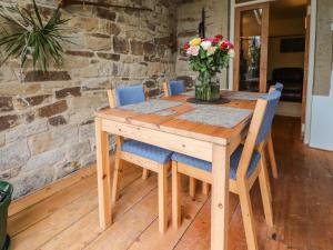 une table en bois avec des chaises et un vase de fleurs dans l'établissement Ribble Valley Cottage, à Preston