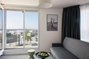 sala de estar con sofá y balcón en The Originals Residence, Le Wax, Lille Est en Villeneuve d'Ascq