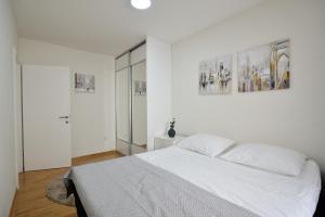 a white bedroom with a white bed and two pictures on the wall at Captain's Luxury Apartments in Mostar +26 photos