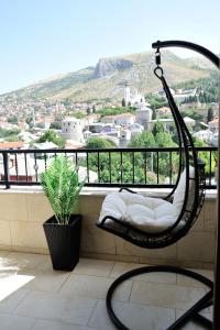 a chair on a balcony with a view of a city at Captain's Luxury Apartments in Mostar