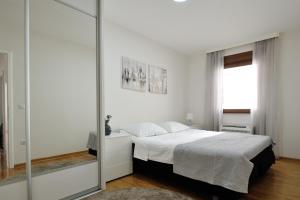 a white bedroom with a bed and a mirror at Captain's Luxury Apartments in Mostar