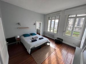een slaapkamer met een bed met blauwe kussens en ramen bij Grande maison avec 5 chambres in Saint-Omer