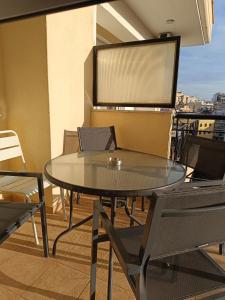 a glass table and chairs on a balcony at Kalvou Flat2 in Thessaloniki
