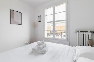 Un dormitorio blanco con una cama con toallas. en Cosy 2 pieces proche metro - Paris 13 - 4P, en París
