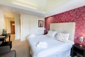 a bedroom with a large white bed with pink wallpaper at The Kings Head Country Hotel in Great Bircham